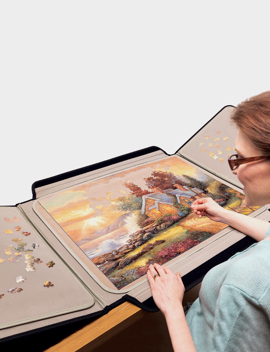 Woman working on a jigsaw on a folding Portapuzzle board