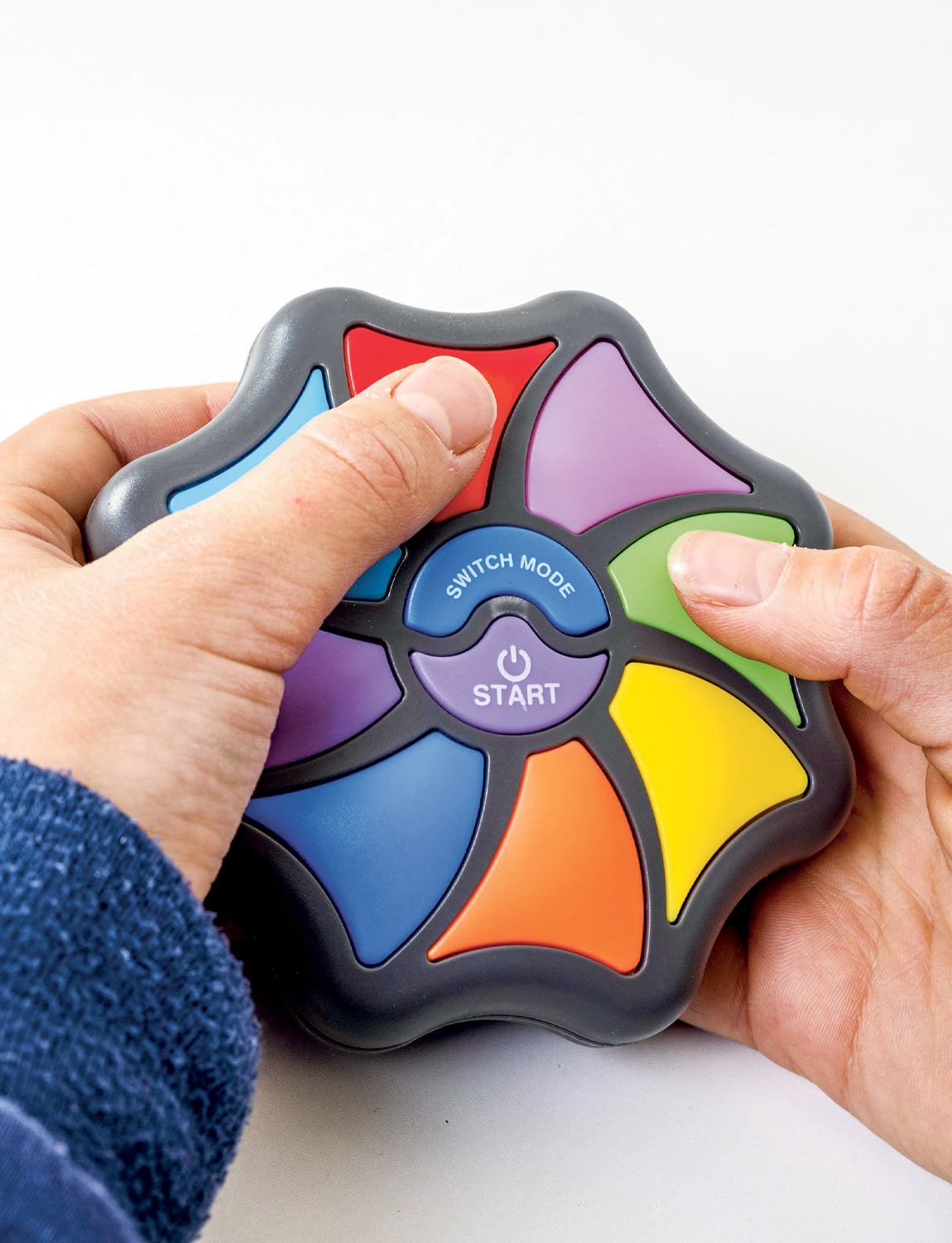 Hands holding the colourful Memory Master handheld game