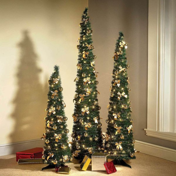 Pre-lit pop-up slimline Christmas trees in three heights beside a window