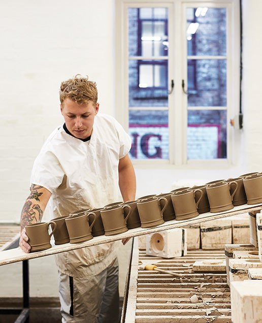 A potter carrying a board of mugs at the Emma Bridgewater factory in Stoke-on-Trent