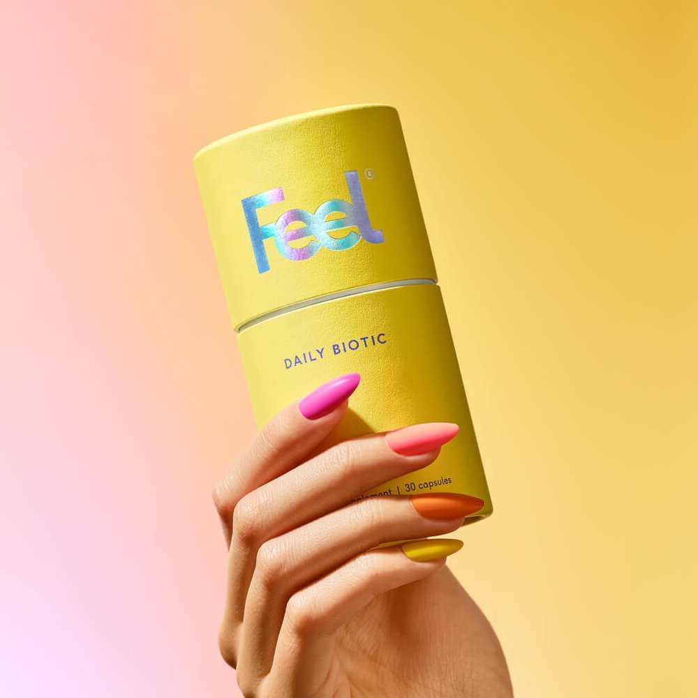 Hand holding a tub of Feel Daily Biotic