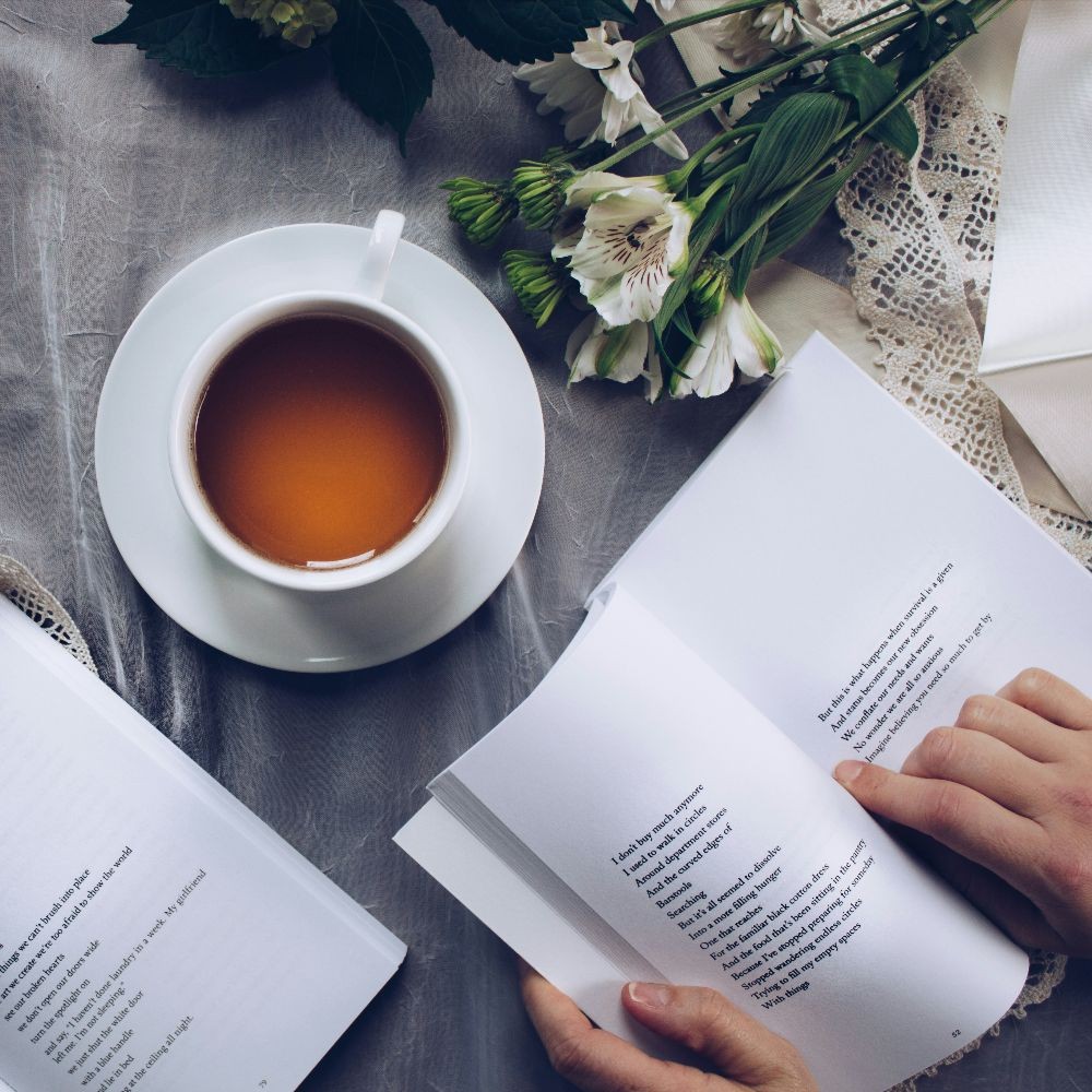 Open book next to a cup of tea and autumn flowers