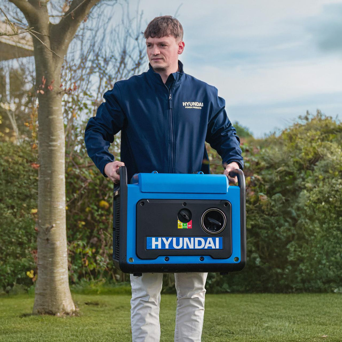 Man carrying a Hyundai HY3250SEi inverter generator