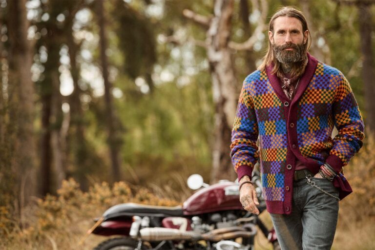 Joe Browns Men’s Knitwear AW26: Patchwork, Aztec and Preppy Cardigans Explained Joe Browns model in a colourful patchwork cardigan leaning on a classic truck