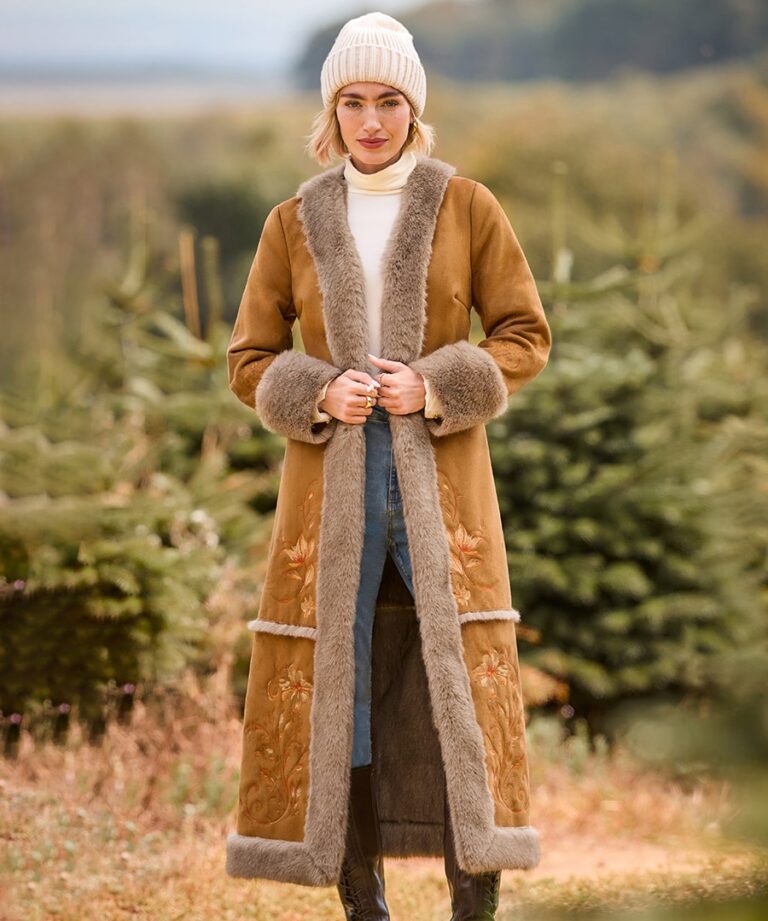 Joe Browns Women’s Winter Coats AW26: Velvet, Moleskin, Tweed or Faux Fur? Woman in the Joe Browns Winter Boho Fur Lined Embroidered Coat in a winter garden