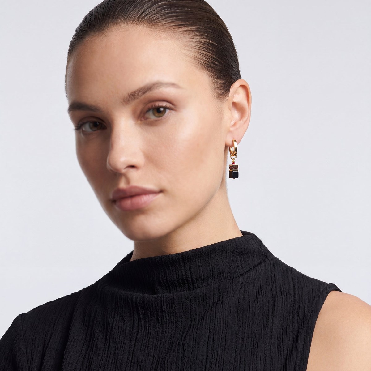 Model wearing Coeur De Lion GeoCUBE Precious Classic hoop earrings in Ruby Noir