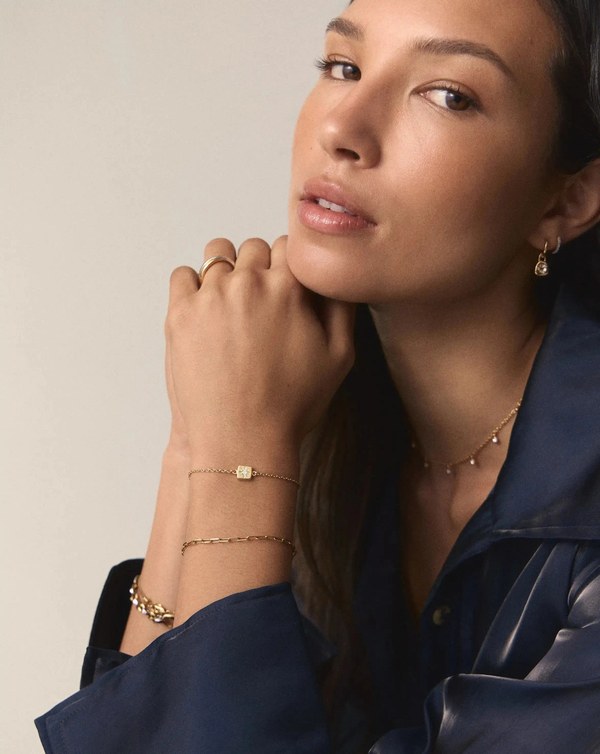 Woman wearing a Missoma June Birthstone Slider Bracelet stacked with a second chain bracelet
