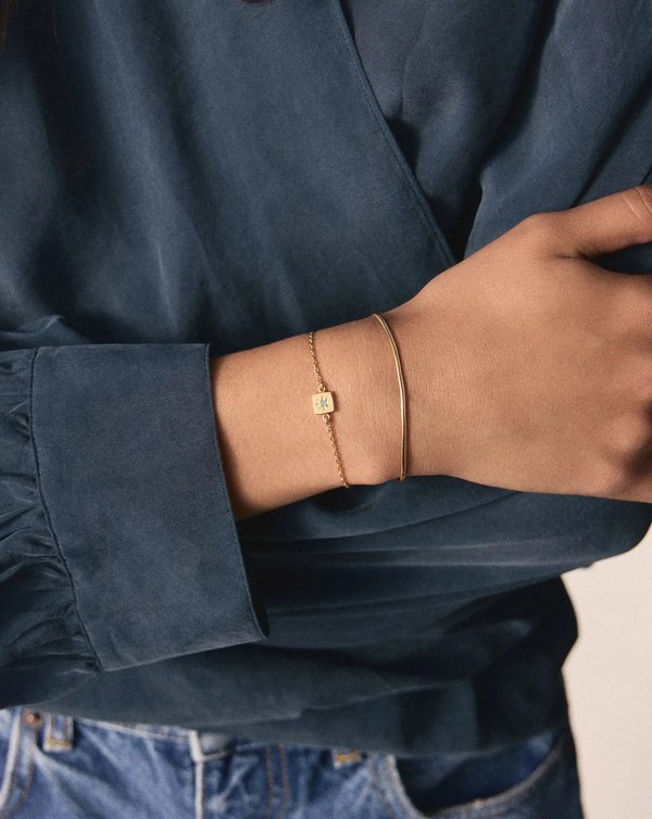 Wrist wearing a Missoma March Birthstone Slider Bracelet with a milky aquamarine stone