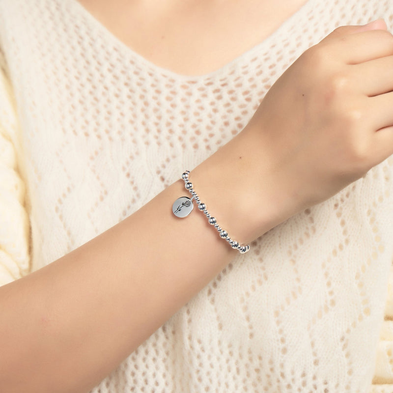 A woman wearing a Philip Jones silver birth flower beaded stretch bracelet