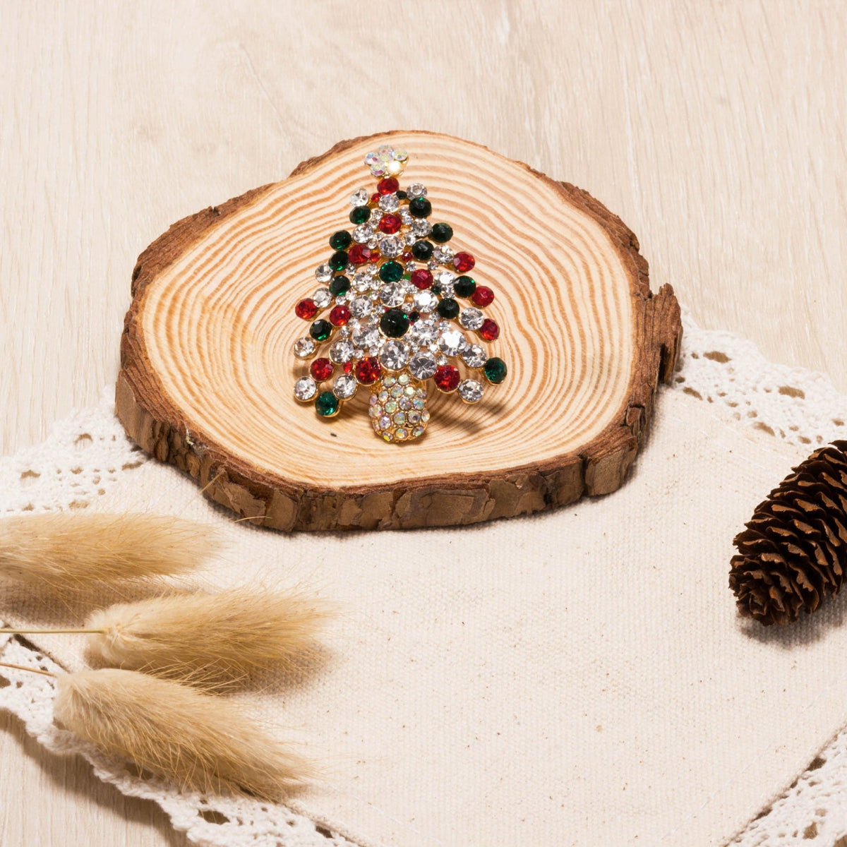 Philip Jones gold plated Christmas tree brooch with coloured crystals on a wooden slice