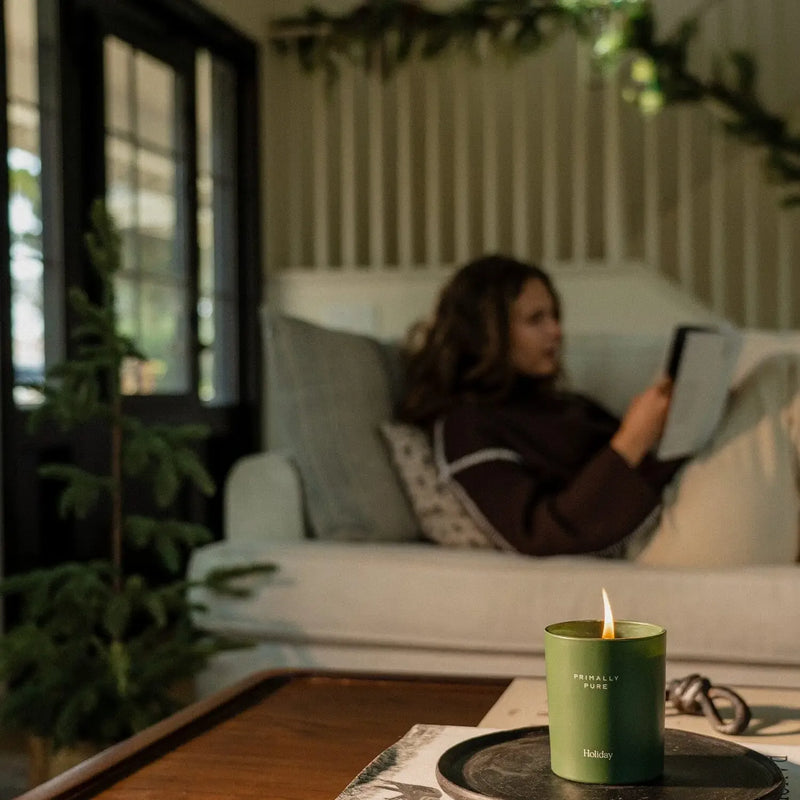 Primally Pure Holiday Candle burning in a cosy living room