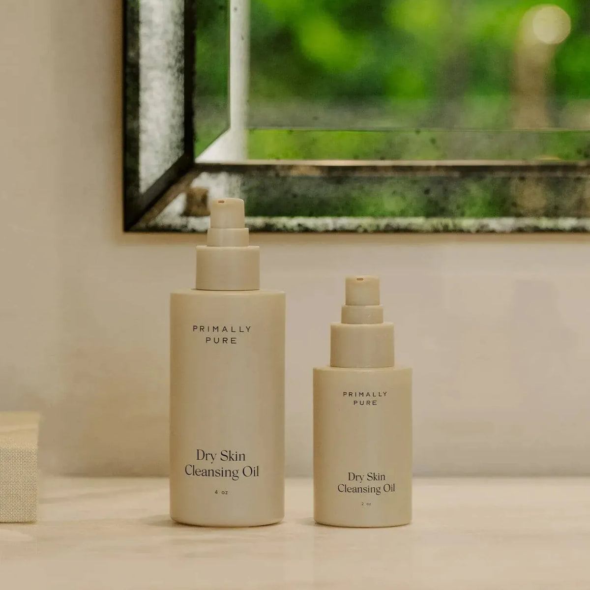 Two bottles of Primally Pure Dry Skin Cleansing Oil on a bathroom shelf