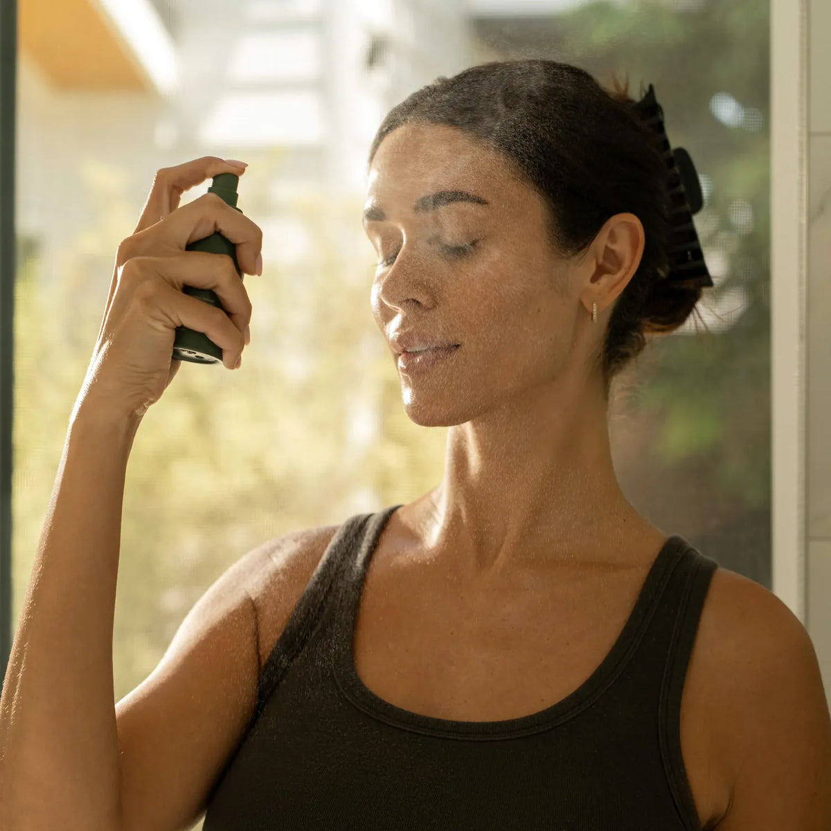 Woman spraying Primally Pure Plumping Mist on her face