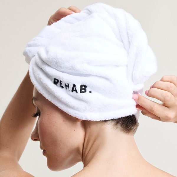 REHAB. Wash Day Explained: Shampoo Milk, Conditioner Milk or Plastic-Free Sheets? Woman wrapping her hair in a white REHAB. micro-fibre hair towel