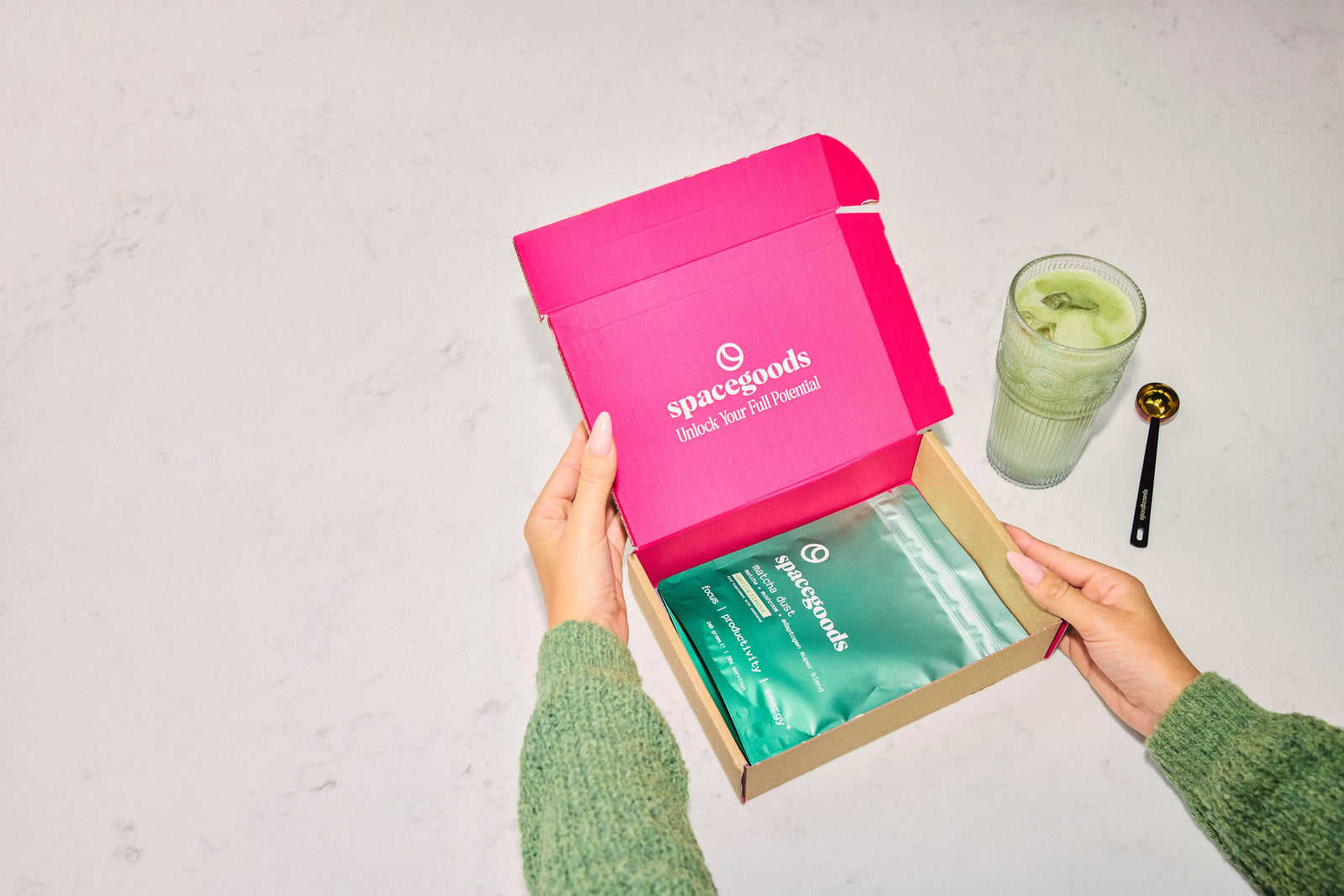 Hands opening a pink Spacegoods sample box of Matcha Dust sachets