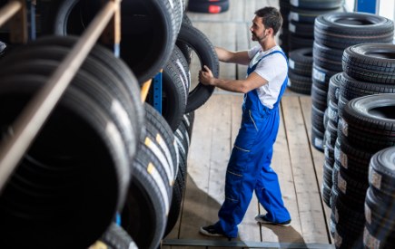 Tyre fitter handling tyres in a tyre warehouse