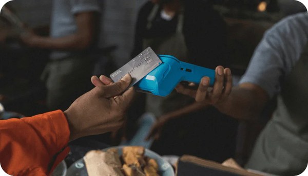 Hands holding a phone and a bank card at a cafe table