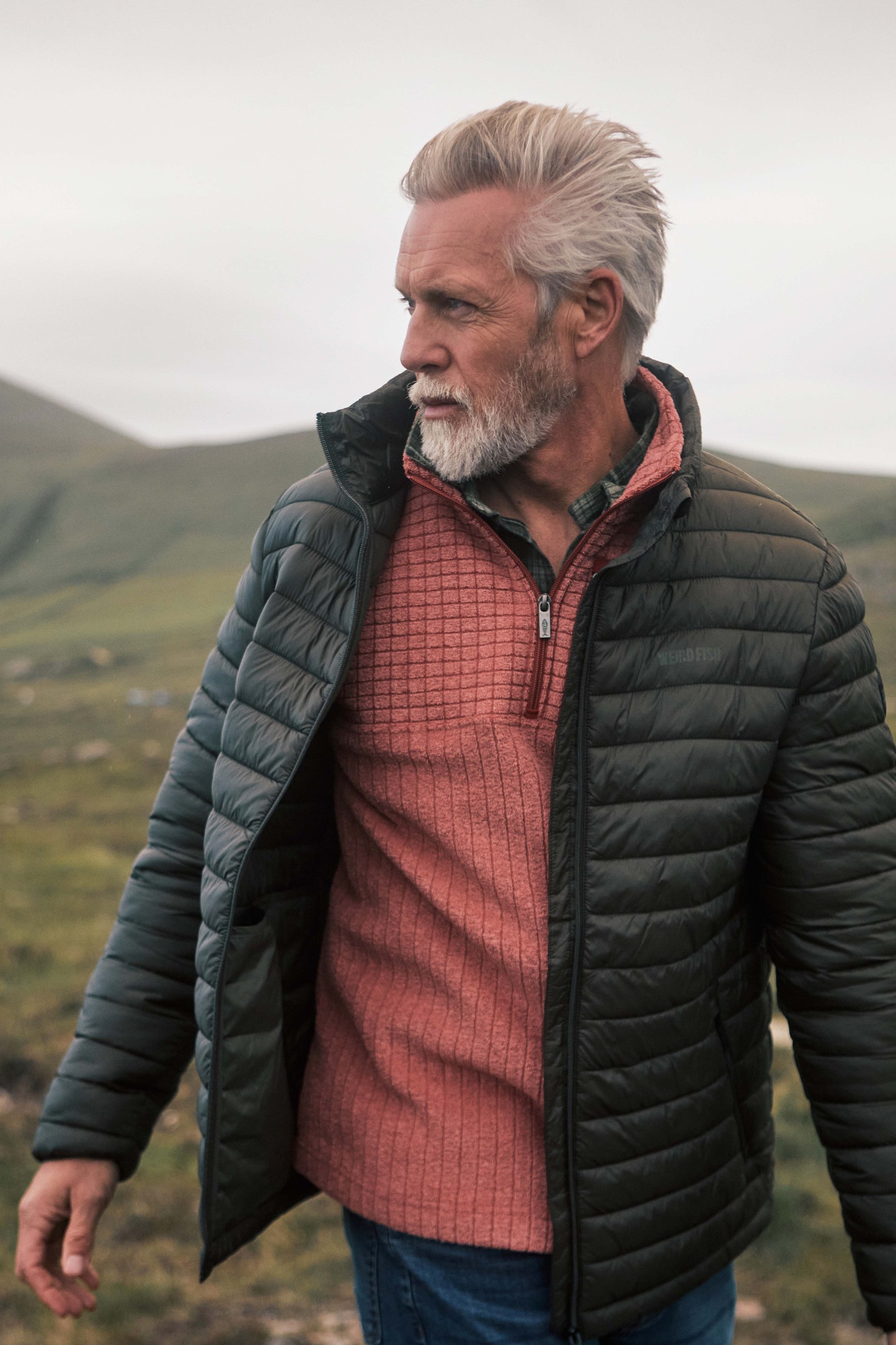 Man wearing the Weird Fish Longmont quarter zip stripe grid fleece under a padded jacket
