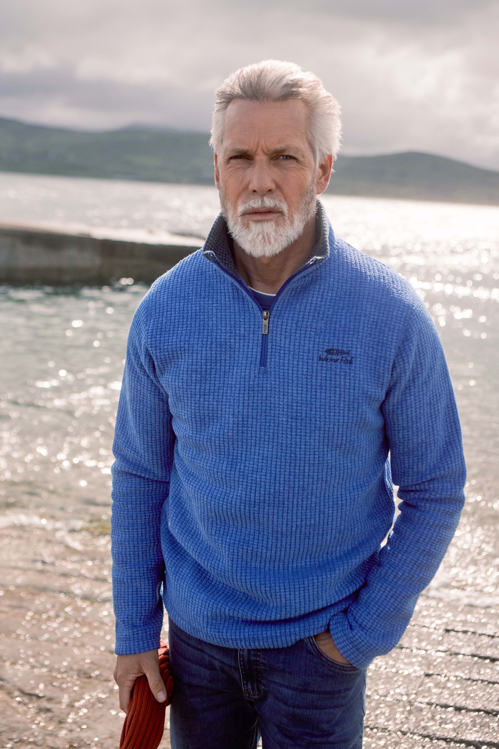 Man wearing a blue Weird Fish Newark quarter zip grid fleece by the sea