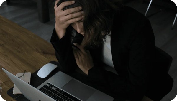 Person resting their head in their hand in front of a laptop