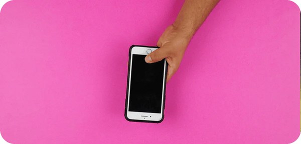 Hand holding a smartphone against a bright pink background